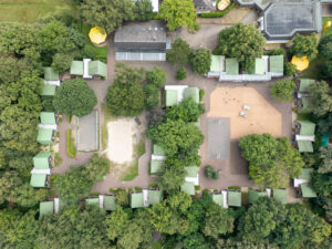 Luftaufnahme von ca. einem Dutzend Ferienhütten zwischen grünen Bäumen